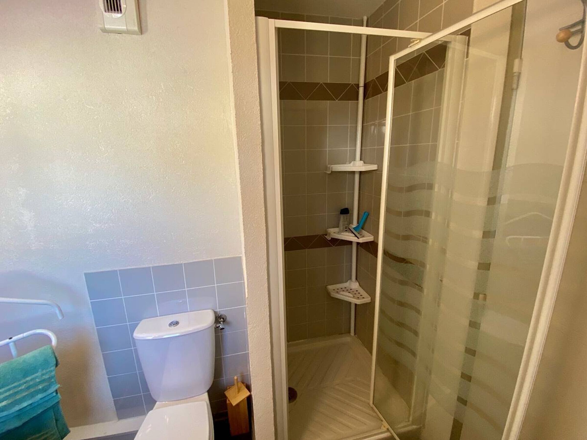 Un baño con inodoro, cabina de ducha y barra para toallas.