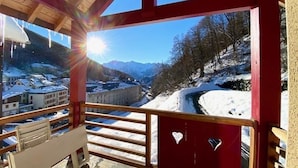 A wooden balcony with a view of a snowy landscape and mountains.