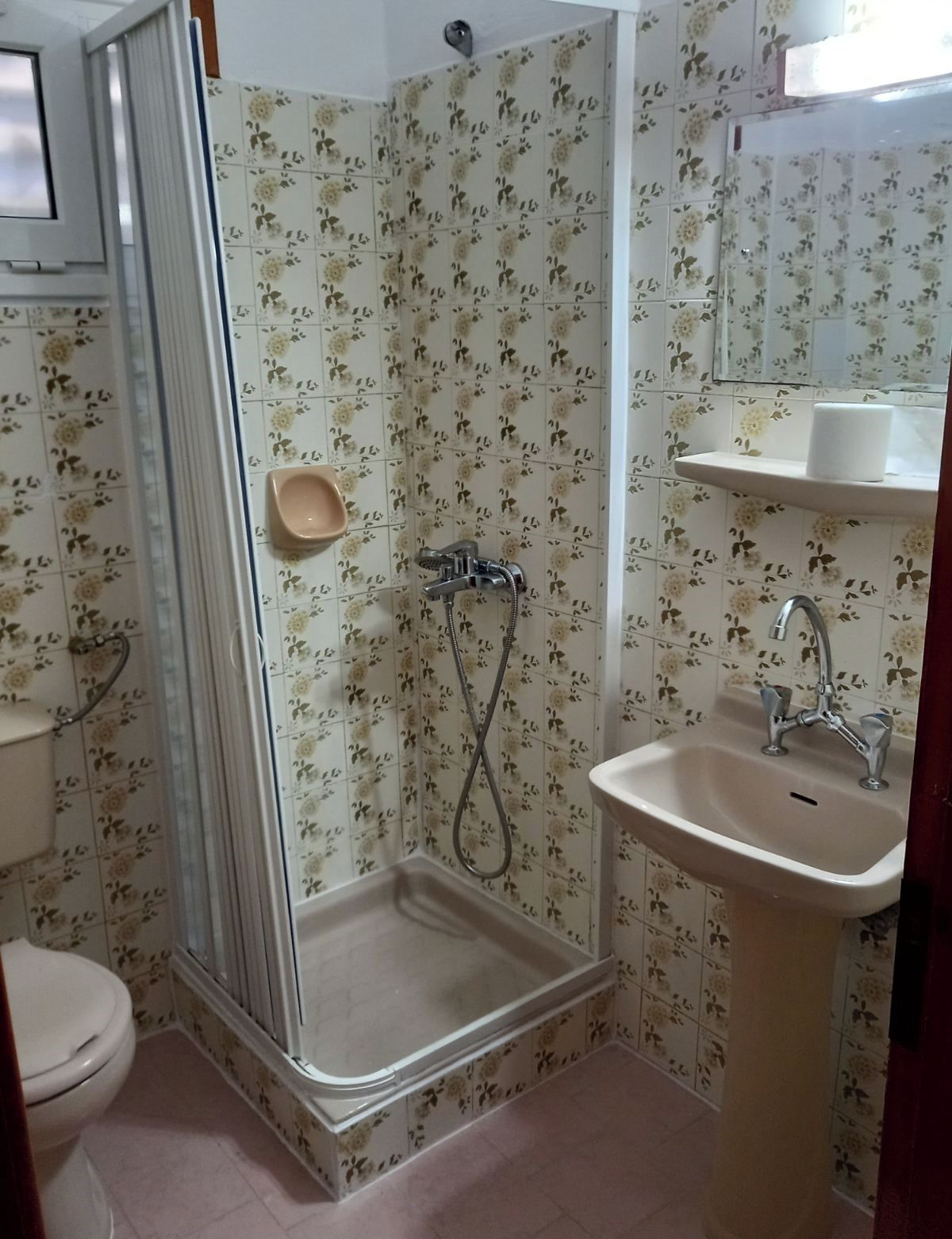 Un baño con ducha, inodoro, lavamanos y espejo.