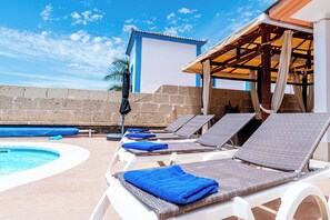 Zona de piscina con sillones de descanso y una alberca.