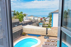 A residential area with a swimming pool, a view of the sea, and a clear sky.