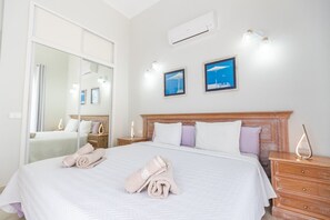 Una habitación de hotel con una cama grande, una mesita de noche, un espejo y dos cuadros en la pared.