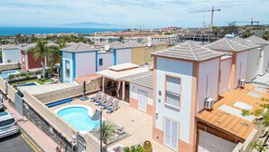 A residential area with a swimming pool, lounge chairs, and a view of the sea. - Villa with pool in Madroñal Fañabe, Costa Adeje (Costa Adeje)