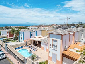 Zona residencial con piscina, sillas de descanso y vista al mar.