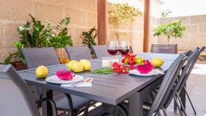 An outdoor dining area with a table set for two, featuring a variety of fruits, two glasses of red wine, and a candle. - Villa with pool in Madroñal Fañabe, Costa Adeje (Costa Adeje)