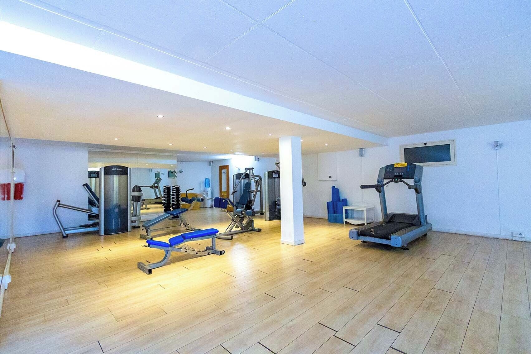 A spacious gym with various exercise equipment, including treadmills and weight machines.