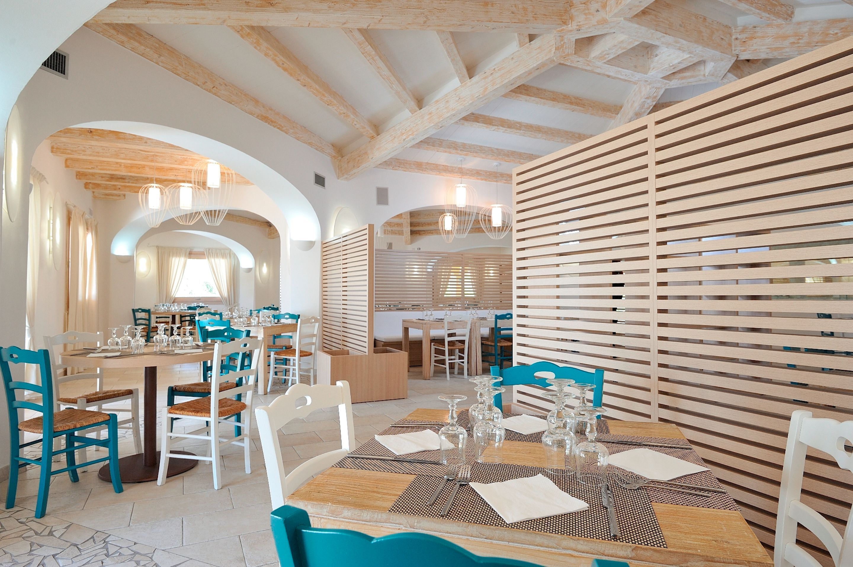 A restaurant with wooden beams, blue chairs, and tables set for dining.