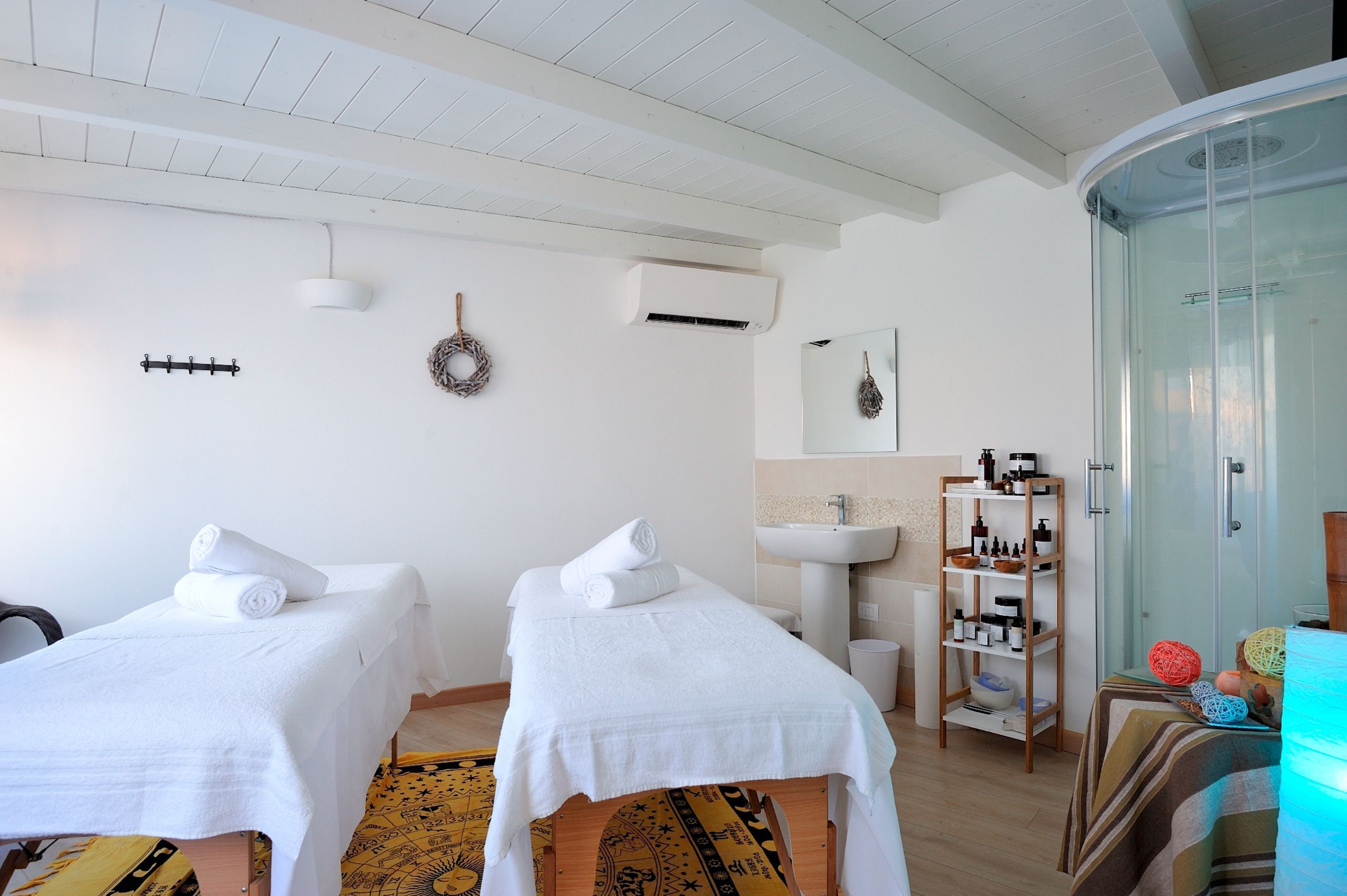 A room with two beds, a sink, and a glass shower enclosure.