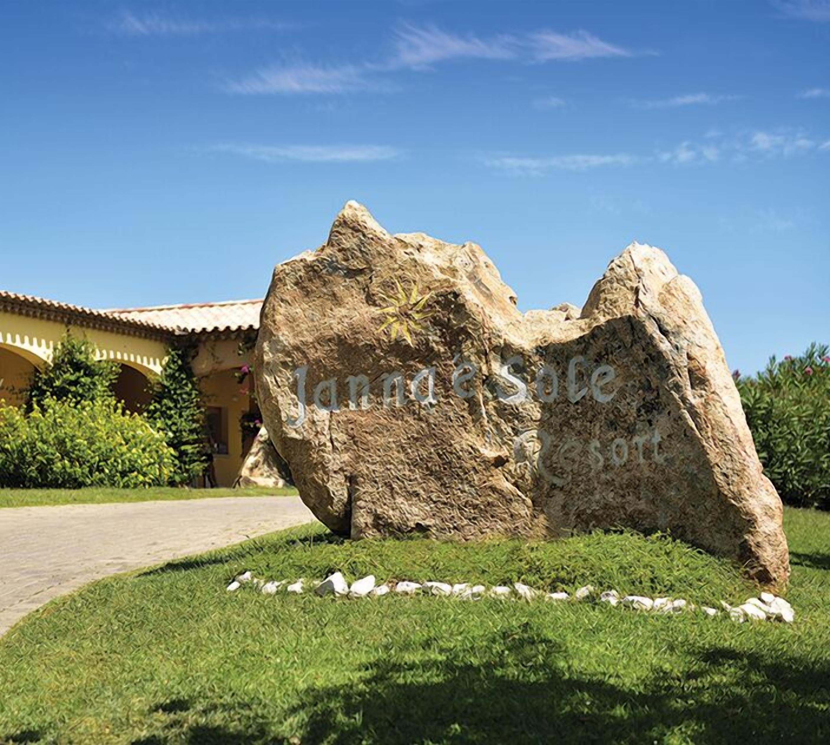 A large rock formation in front of a building with a tiled roof and a pathway leading to it.