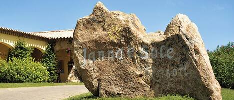 A large rock formation in front of a building with a tiled roof and a pathway leading to it.