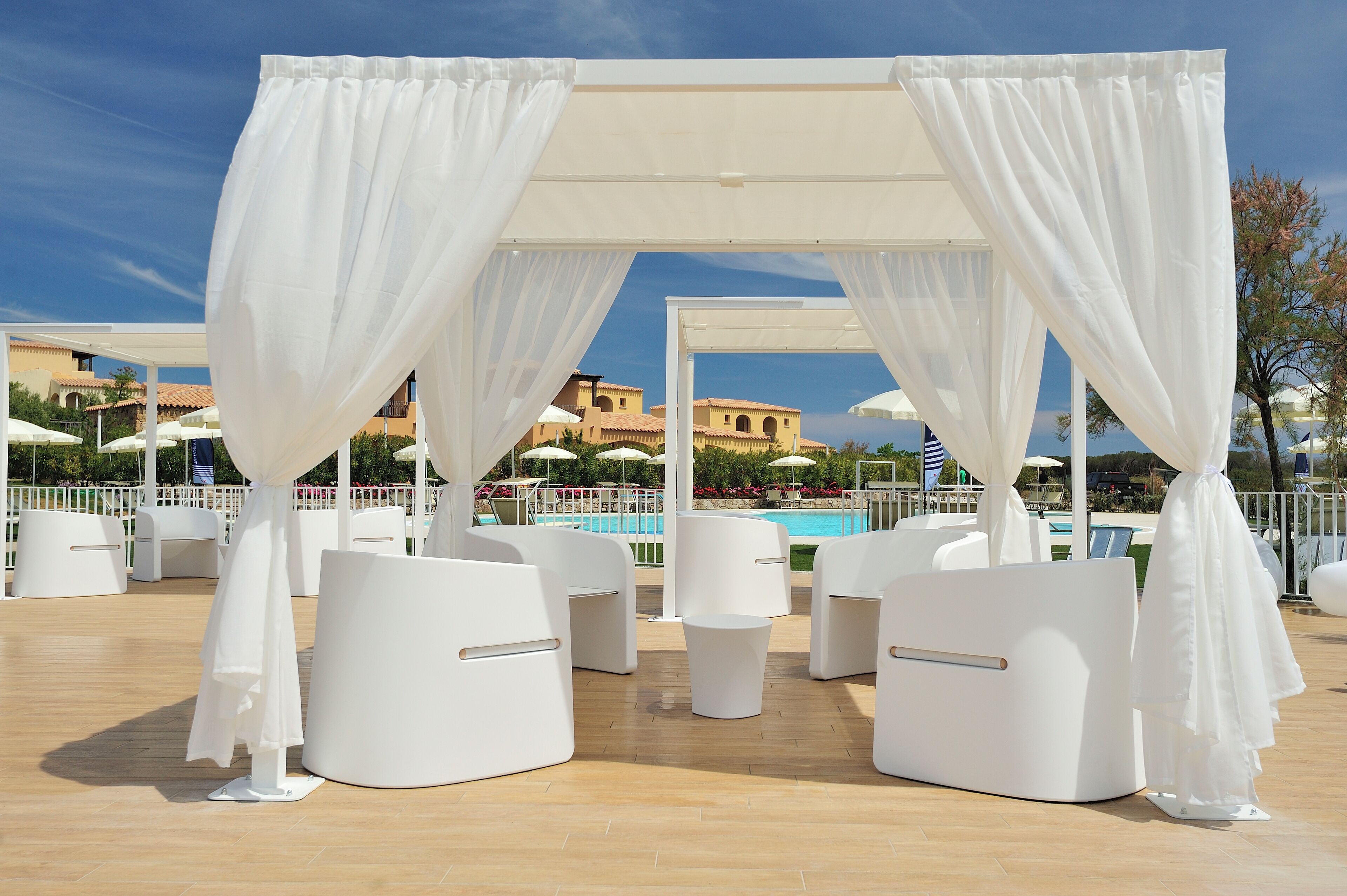 Terraza en la azotea con toldos blancos, sillones de descanso blancos y una piscina al fondo.