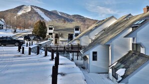 Zona residencial con casas, una calle cubierta de nieve y una montaña al fondo.