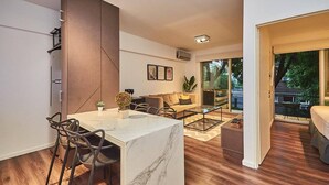 Una sala de estar moderna con una mesa de comedor de mármol, un sofá y una mesa de centro. Hay un ventanal corredero que da a un balcón.
