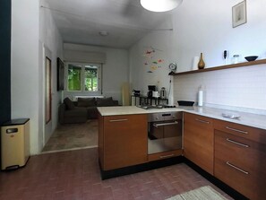 A compact kitchen with a stove, oven, and sink. There is a dining area with a table and chairs, and a living room with a sofa.