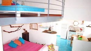 A dormitory-style room with bunk beds, a kitchenette, and a dining area.