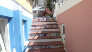 A set of stairs with colorful mosaic tiles leading to a balcony with a railing and a potted plant.