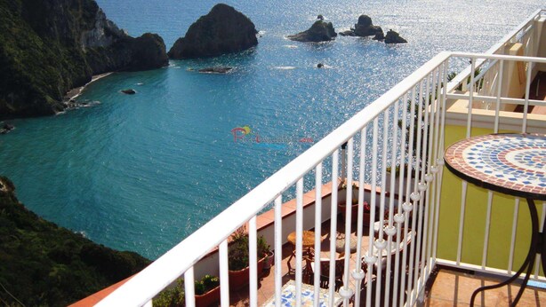 A balcony with a view of the sea and rocky formations.