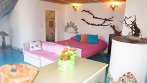 A bedroom with a bed, a sofa, a dresser, and a decorative wall piece.