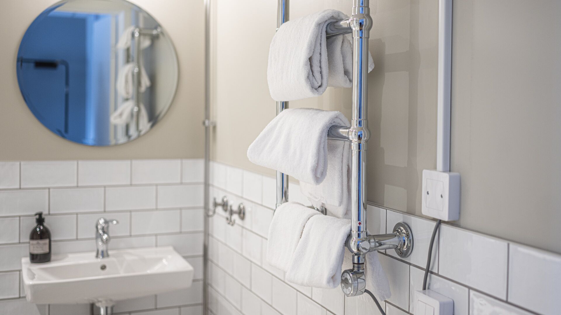 A bathroom with a white sink, a mirror, and two towels hanging on a towel rack.