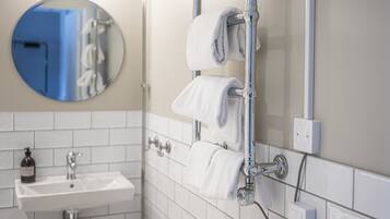 A bathroom with a white sink, a mirror, and two towels hanging on a towel rack.