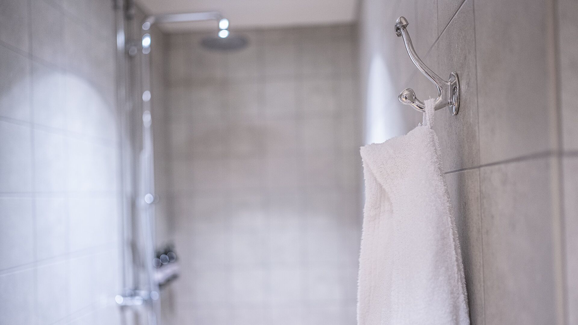 A bathroom with a shower, a towel rack, and tiled walls.