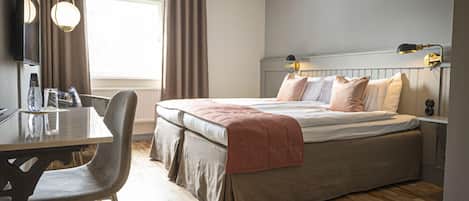 Un dormitorio moderno con cama, mesita de noche y escritorio con sillas.