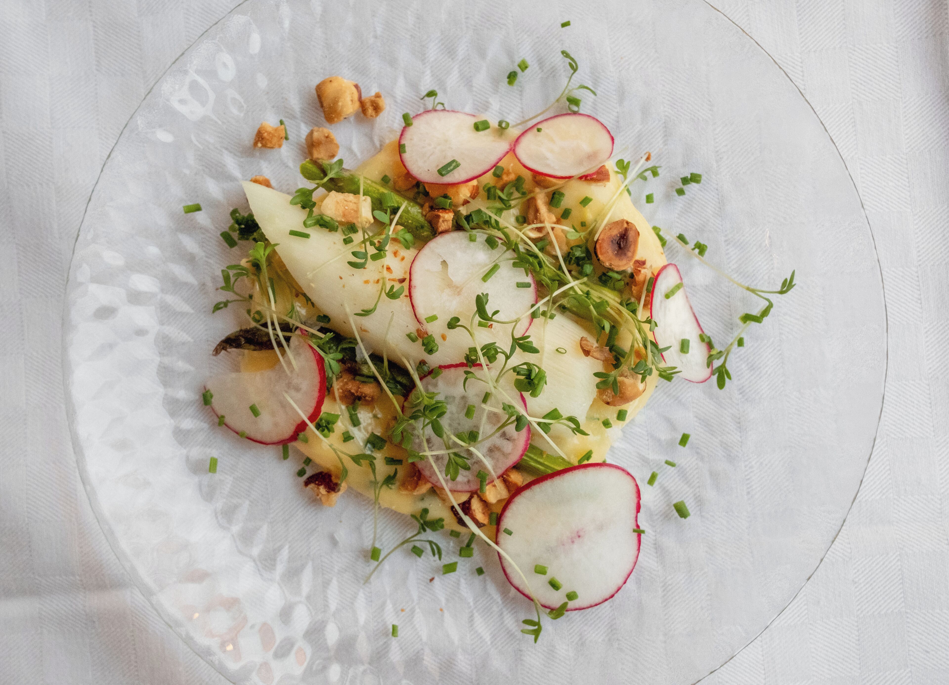 Une assiette de nourriture contenant des radis, des jeunes pousses et des noix.