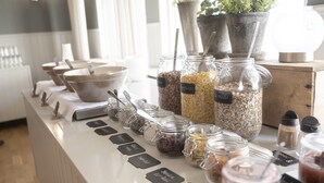Un buffet con diversi cibi esposti in vasetti e ciotole, etichettati con nomi come 'funghi' e 'carote'.