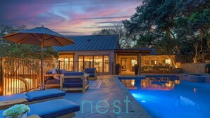 A poolside area with lounge chairs, a covered seating area, and a house with a pool. - ***NEW*** 7 MINUTES TO DOWNTOWN | POOL | HOT TUB | POOL TABLE | FOOSBALL | FIRE PIT | 13 Queen Beds (Austin)