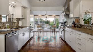 A modern kitchen with a central island, large windows, and a view of the outdoors. - ***NEW*** 7 MINUTES TO DOWNTOWN | POOL | HOT TUB | POOL TABLE | FOOSBALL | FIRE PIT | 13 Queen Beds (Austin)