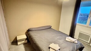Un dormitorio con cama, mesita de noche y ventana con vistas.