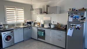 Una cocina moderna con lavadora y secadora integradas, electrodomésticos de acero inoxidable y un refrigerador decorado con fotografías.