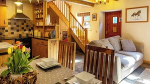 Un ambiente accogliente con tavolo da pranzo apparecchiato, una scala in legno e un angolo living con divano.