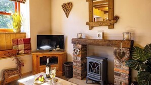 Un accogliente soggiorno con televisore, camino e un ripiano in legno.