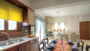 Cocina bien iluminada con un fregadero, estufa y comedor preparado para cuatro personas.