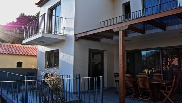 A two-story building with a balcony and patio area. - Casa da Praia Calheta - Moradia (Calheta)