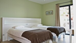 A room with two beds, a window with curtains, and a small table. - Casa da Praia Calheta - Moradia (Calheta)