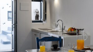 Une cuisine moderne avec un coin repas, comprenant un évier, un panier de fruits et un verre de jus d’orange sur la table.