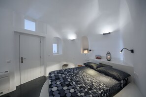A bedroom with a bed, a small window, a wall-mounted light, and a nightstand.