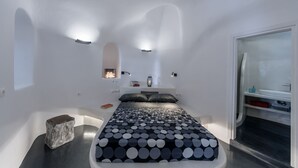 Une chambre à coucher moderne avec un lit, des tables de chevet, une petite fenêtre et un espace douche intégré.