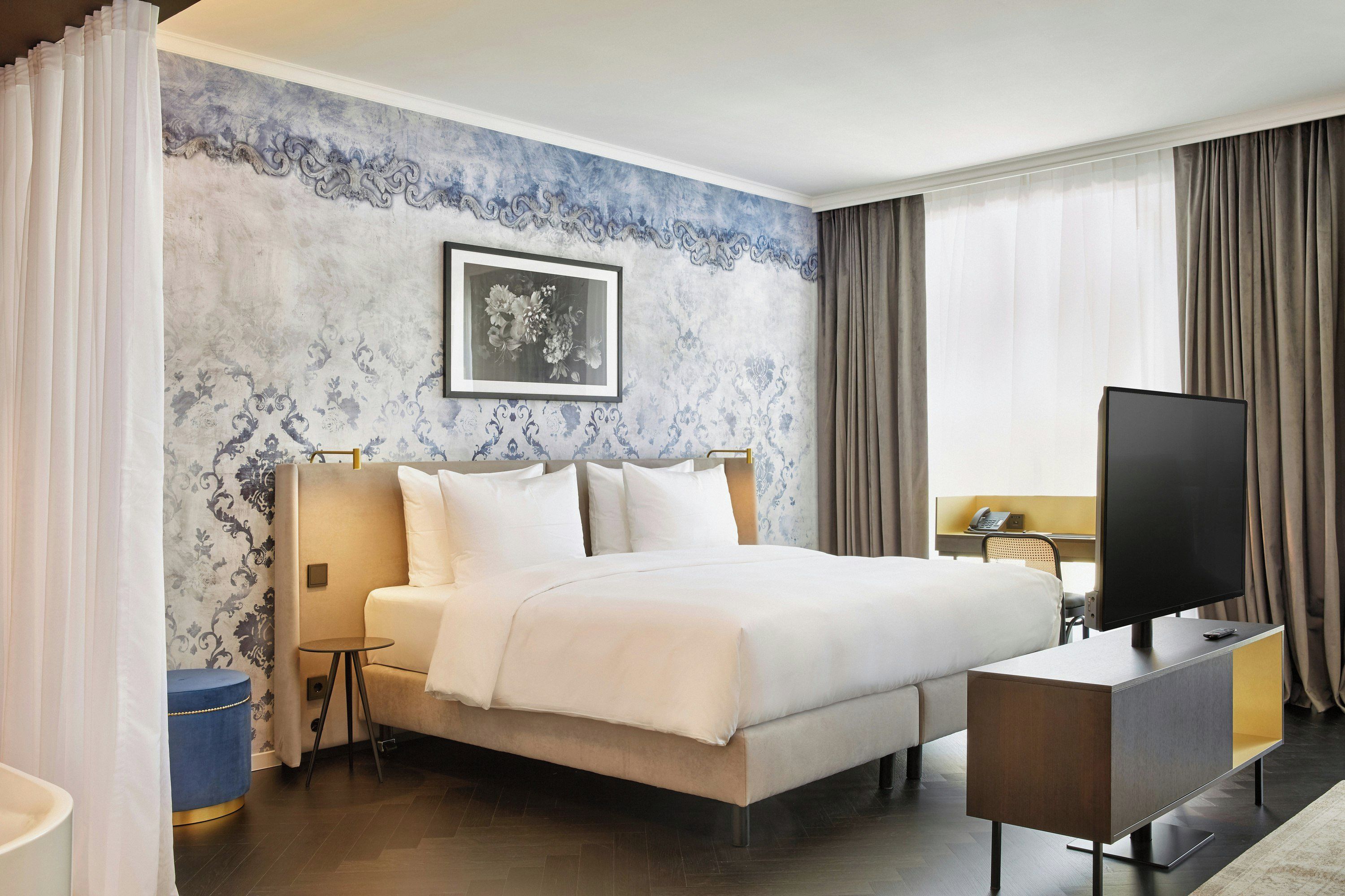 Una habitación de hotel con una cama, televisión, escritorio y una silla.