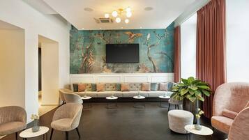 Una sala moderna con sofá, sillas, televisión y un mural grande en la pared.