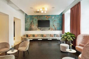 Una sala moderna con sofá, sillas, televisión y un mural grande en la pared.