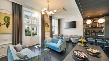 Un salon moderne comprenant un canapé, des fauteuils, une table basse et un coin repas avec un buffet.