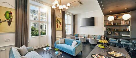 Ein modernes Wohnzimmer mit einer Couch, Sesseln, einem Couchtisch und einem Essbereich inklusive Buffet.