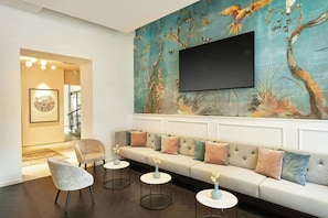 Una sala moderna con sofá, sillas y un mural en la pared con motivos televisivos.
