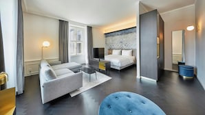 Una habitación de hotel moderna con sofá, cama, escritorio y un ventanal grande.