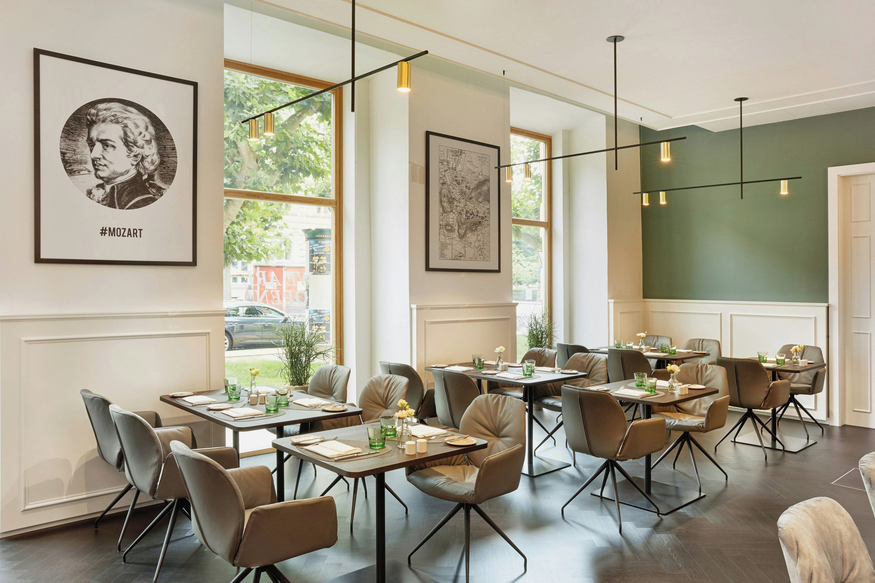 A restaurant interior with multiple tables, chairs, and framed artwork on the walls.
