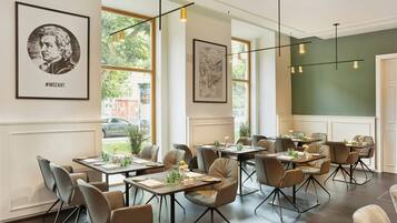 A restaurant interior with multiple tables, chairs, and framed artwork on the walls.
