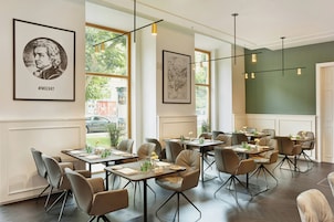 Interior de restaurante con varias mesas, sillas y cuadros en las paredes.